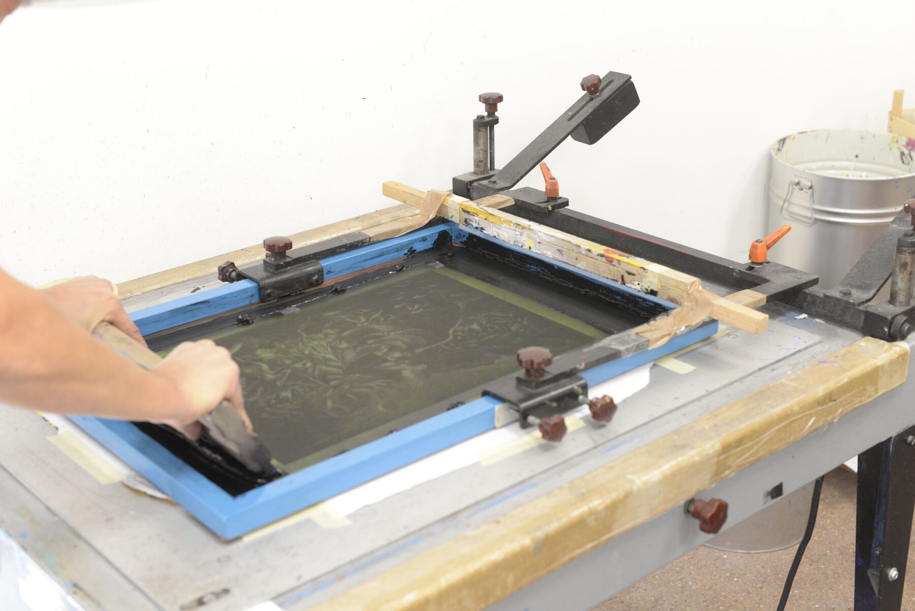 A printer finishing a print by hand, the artwork emerging from the ink