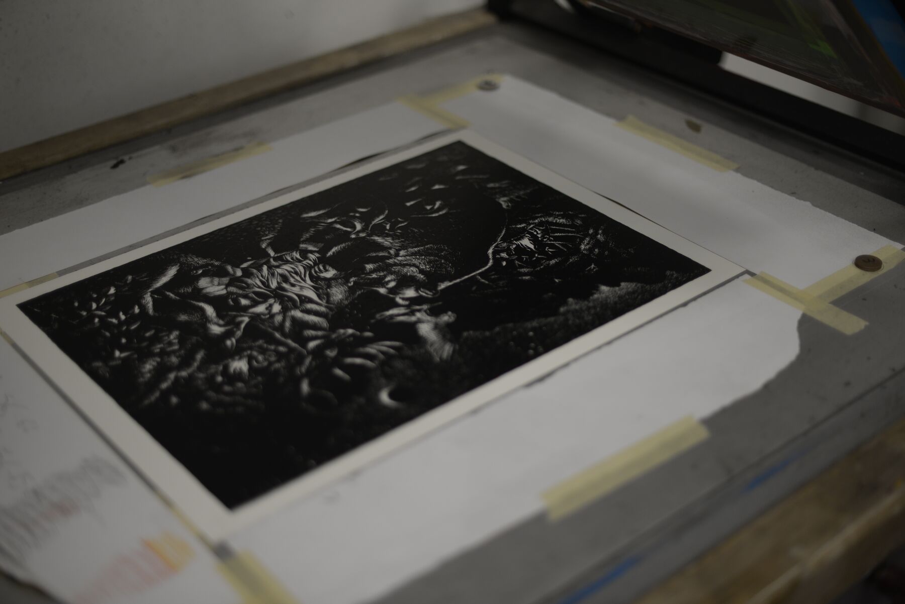 The freshly screen-printed Bonfire artwork visible on paper beneath the raised screen