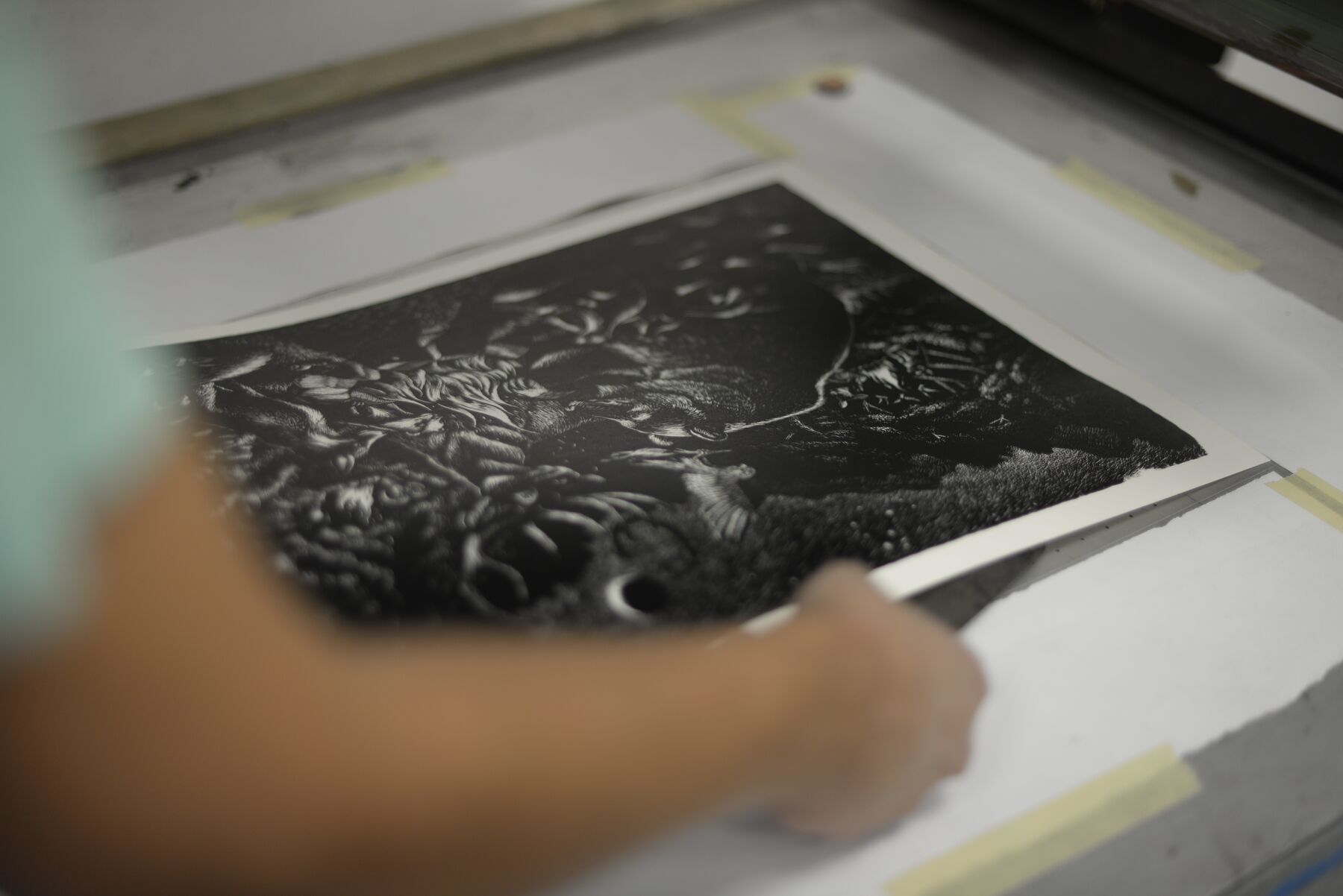 A printer checking the coverage and placement of a fresh Bonfire screen print